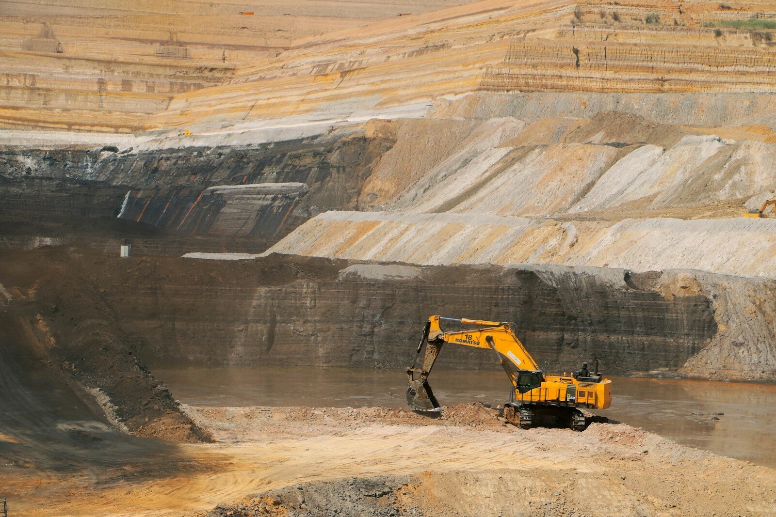 a yellow excavator in a large open pit