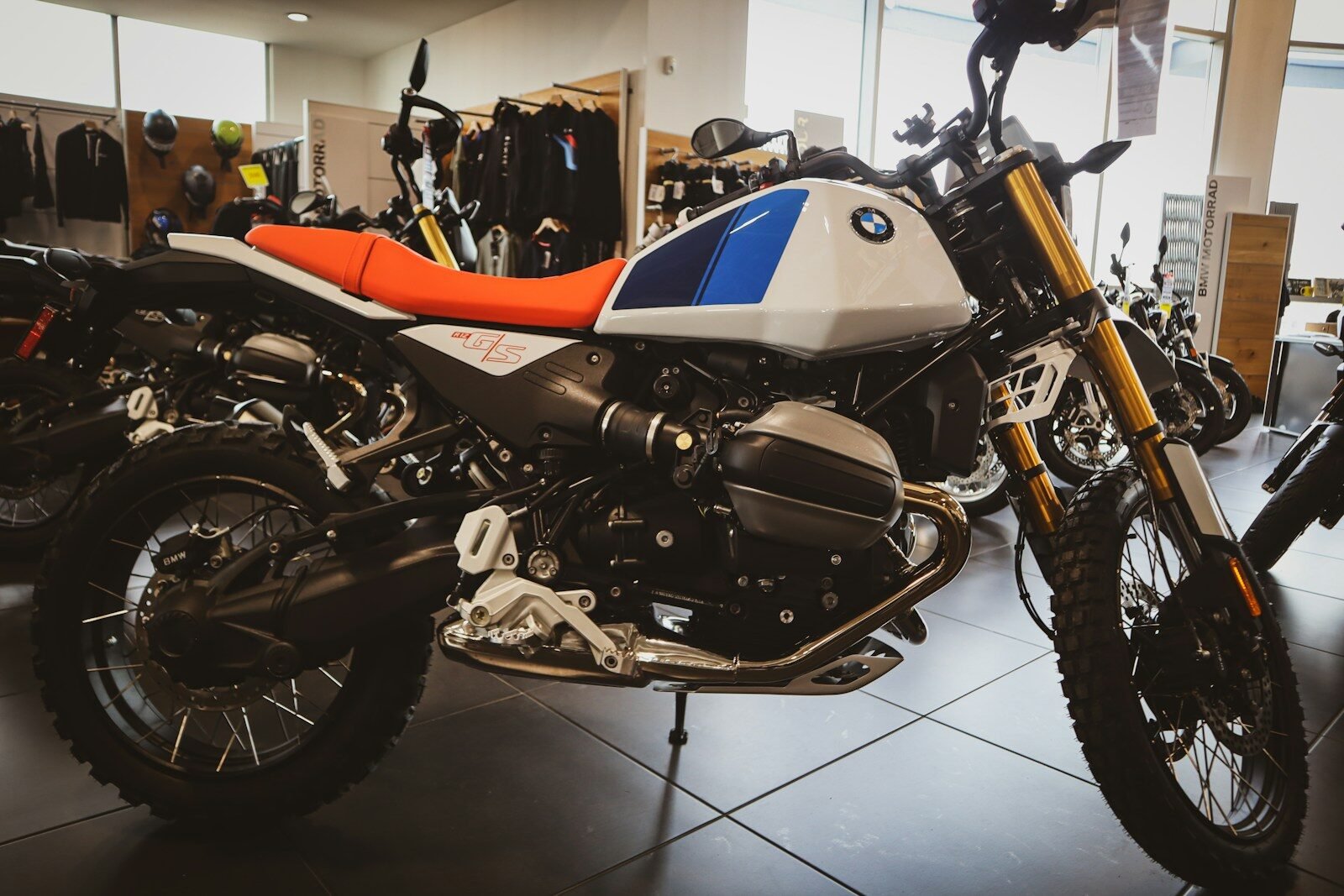 A white and blue BMW motorcycle with an orange seat.