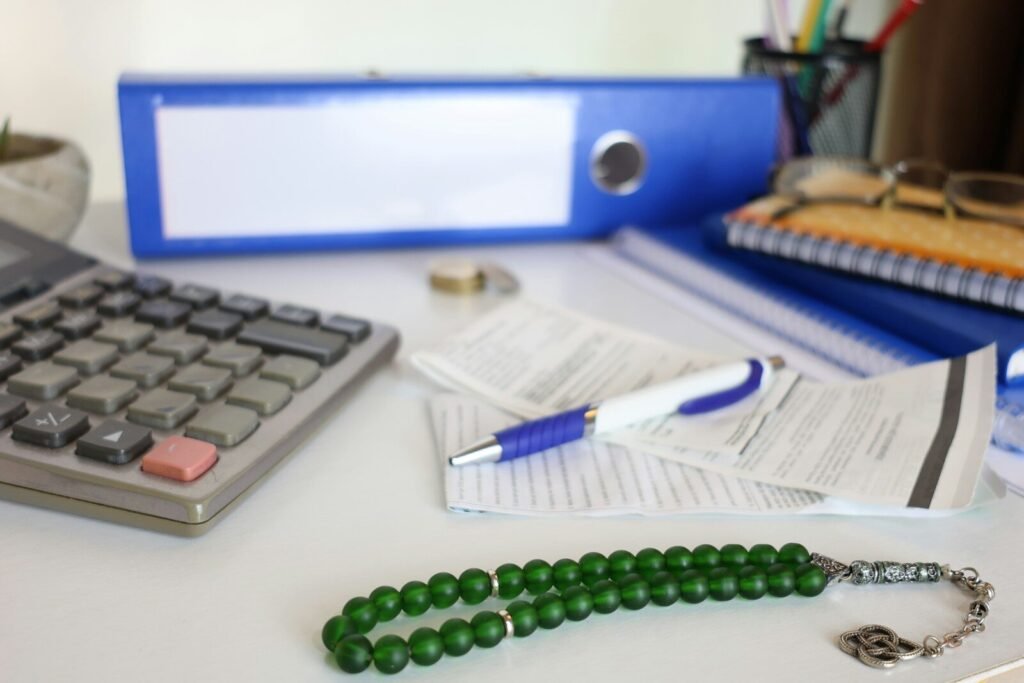 Desk with calculator, papers, and prayer beads.