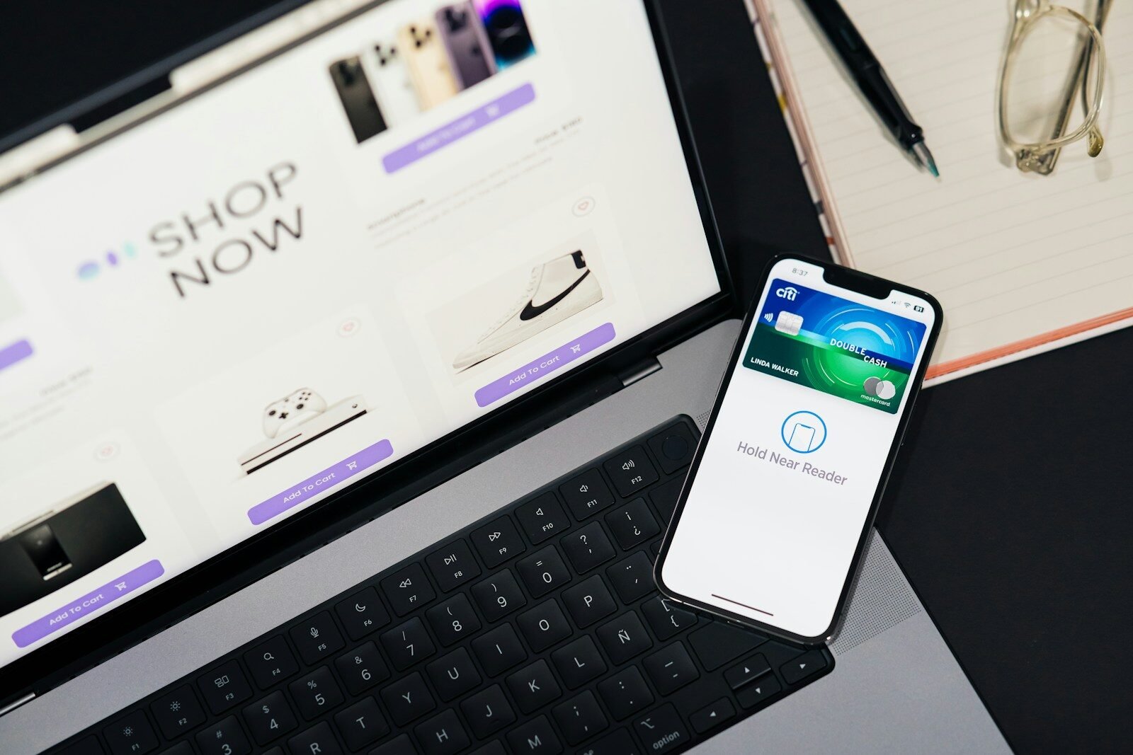 A cell phone sitting on top of a desk next to a laptop